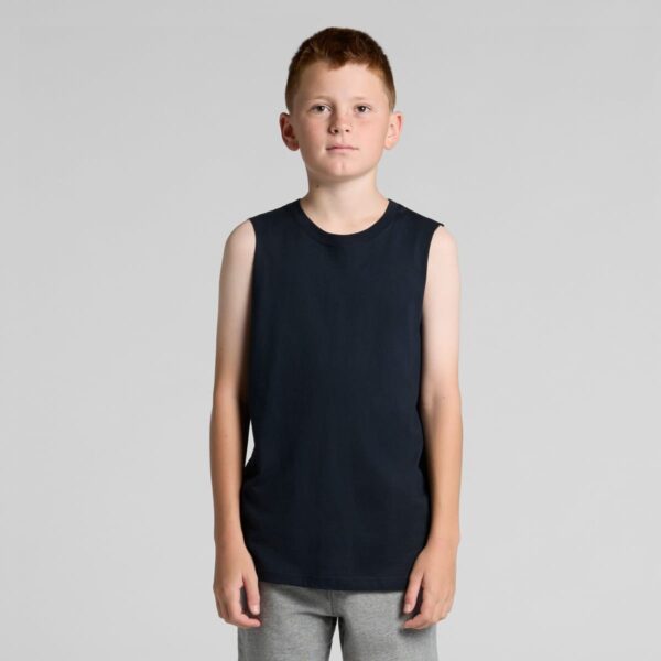 Young boy with short hair wearing a sleeveless black shirt and gray pants, standing still.