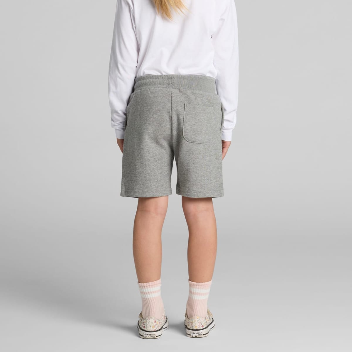 Person wearing gray shorts, white long-sleeve shirt, socks, and sneakers, seen from behind.
