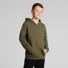 A boy in an olive green hoodie stands with his hand in the pocket, smiling.