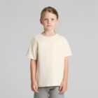 Young child with light brown hair in a cream t-shirt and gray pants, standing against a gray background.