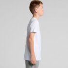 Boy in a white t-shirt and gray pants standing in profile against a plain background.