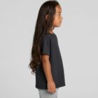 Young child with long hair in a black t-shirt and gray pants, standing in profile.