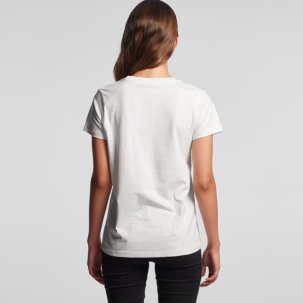 Woman facing away, wearing a plain white t-shirt and black pants against a gray background.