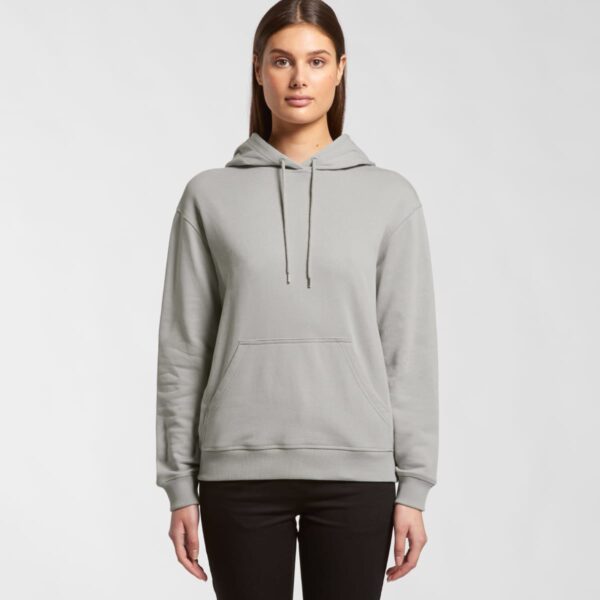 Woman wearing a light gray hoodie and black pants, standing against a plain background.