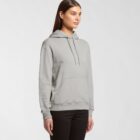Woman in a gray hoodie and black pants standing against a plain white background.