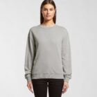 Woman wearing a plain gray sweatshirt and black pants, standing against a white background.