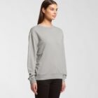 Woman wearing a plain gray sweatshirt and black pants, standing against a white background.
