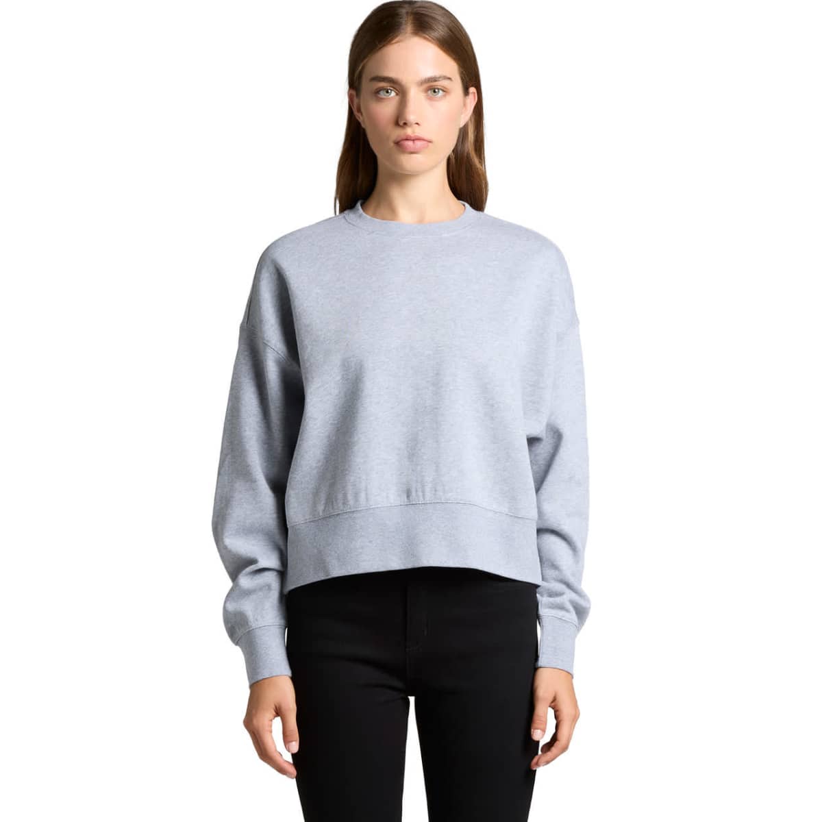 Woman wearing a light gray sweatshirt and black pants, standing against a white background.