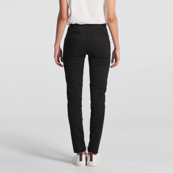 Person wearing black pants and white shoes, shown from the back against a plain background.
