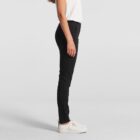 Person in black pants, white top, and white shoes standing sideways against a plain background.