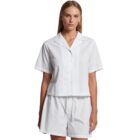 Woman wearing a short-sleeve white button-up shirt and matching white shorts.