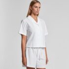Woman wearing a white short-sleeve button-up shirt and matching white shorts.
