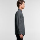 Man wearing a dark gray button-up shirt, standing in profile against a plain background.