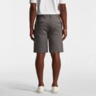 Person wearing gray shorts, white shirt, and white shoes, standing with back facing camera.