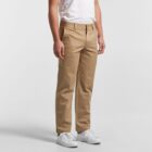 Person wearing khaki pants, white t-shirt, and white sneakers standing against a plain background.
