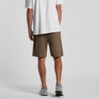 Person wearing a white shirt, brown shorts, and gray sneakers, shown from the back.