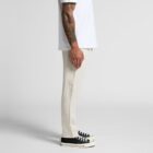Person in a white shirt, beige pants, and black sneakers, standing sideways.