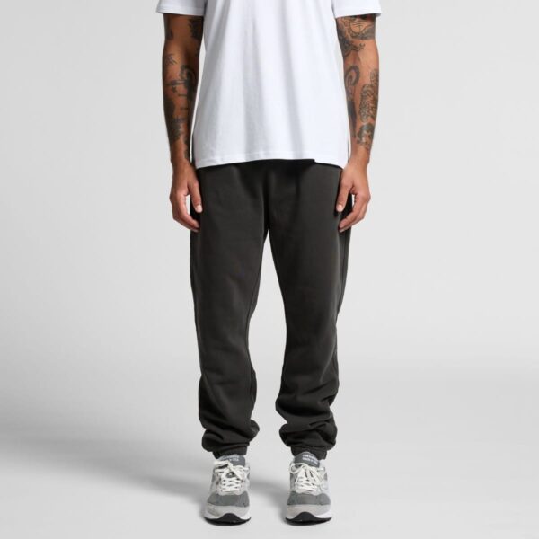 Man in white t-shirt, black joggers, and gray sneakers standing against a plain background.