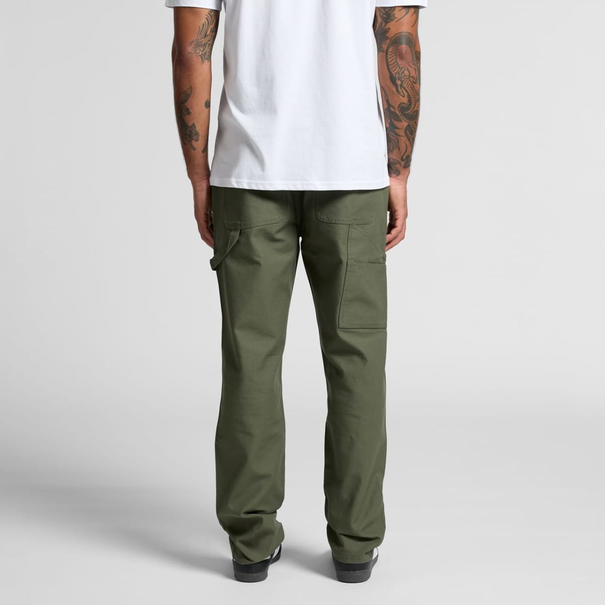 Person in a white t-shirt and green pants, shown from the back, standing on a gray floor.