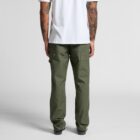 Man in white t-shirt and green cargo pants, shown from the back, standing on gray floor.