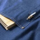 A denim pocket holding a spiral notebook and a silver pen clipped to the edge.