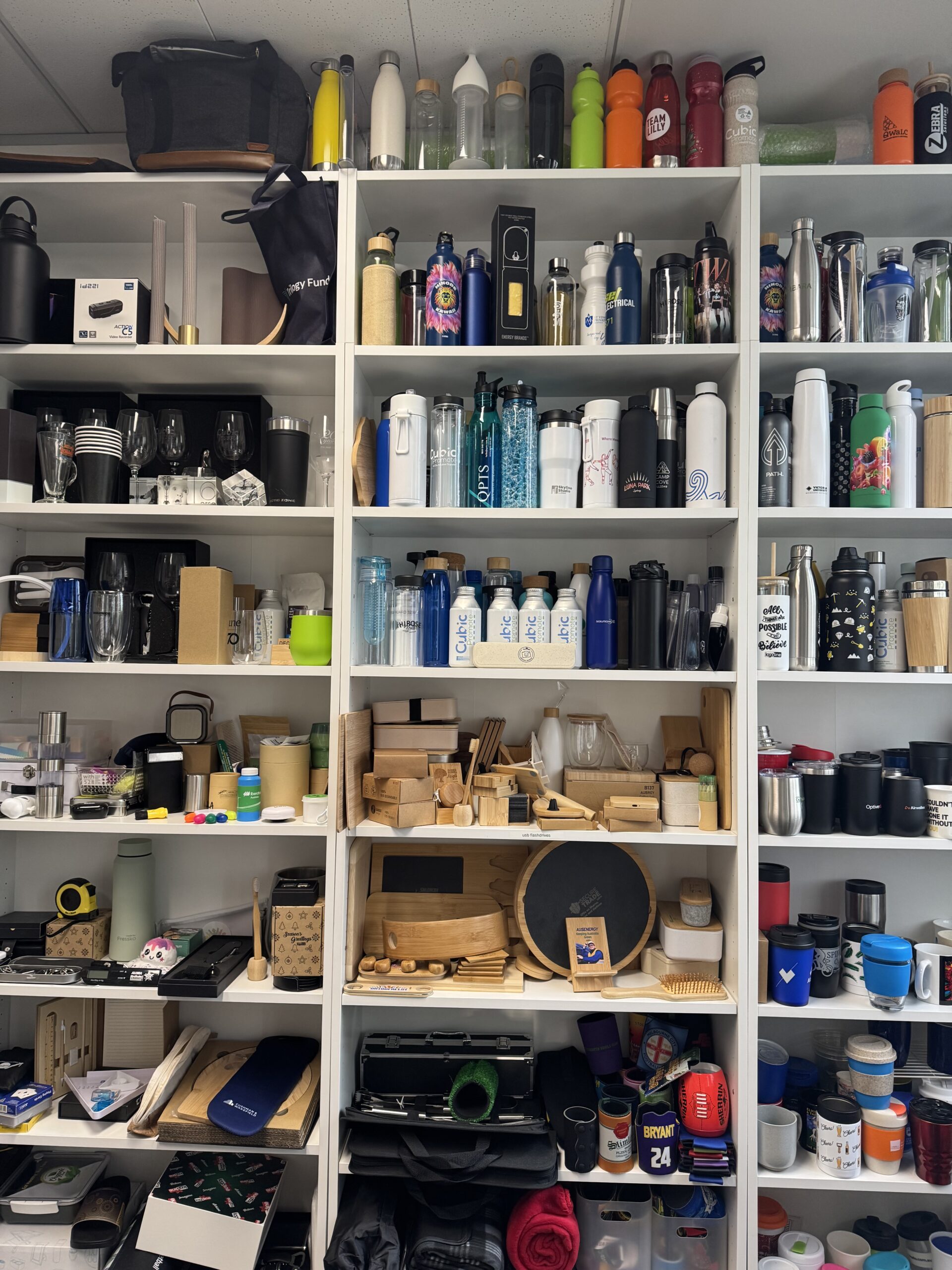 Shelves filled with kitchenware and water bottles—buy merch Factory Direct from Cubic Promote.