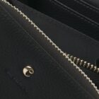 Close-up of a black leather wallet with a gold zipper and a metal logo.