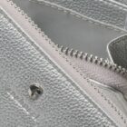Close-up of a silver textured bag with a zipper and a small metal logo.