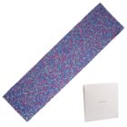 A colorful patterned scarf with a white Carhartt box beside it on a white background.