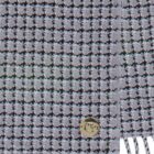 Gray and black checkered fabric with a round gold button and white fringe on the edge.