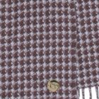 Brown and white houndstooth patterned fabric with a gold button and fringe at the edge.