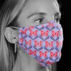 Woman wearing a butterfly-patterned face mask with red butterflies on a light purple background.