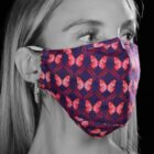 A woman wears a purple mask with red butterfly patterns.