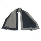 A gray and black scarf with fringed edges laid out flat.