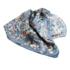 Blue silk scarf with abstract peach, white, and green pixelated pattern, draped loosely.