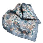 Silk scarf with pastel pixel pattern and Cacharel logo on a gray background.