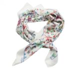 White silk scarf with colorful floral print, loosely folded on a plain background.