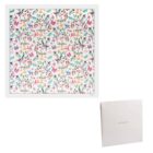 Square floral scarf with colorful flower pattern and a white box nearby.