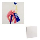 White scarf with abstract red, blue, and yellow design, next to a white Cacharel box.