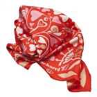 Red and pink patterned silk scarf with heart and floral designs, partially folded.