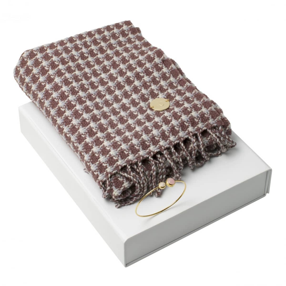 A folded houndstooth scarf and a gold bracelet on a white box.