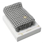 Gray checkered scarf and gold bracelet displayed on a white box.