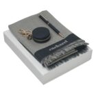 Gray scarf, pen, and round keychain case on a white box.