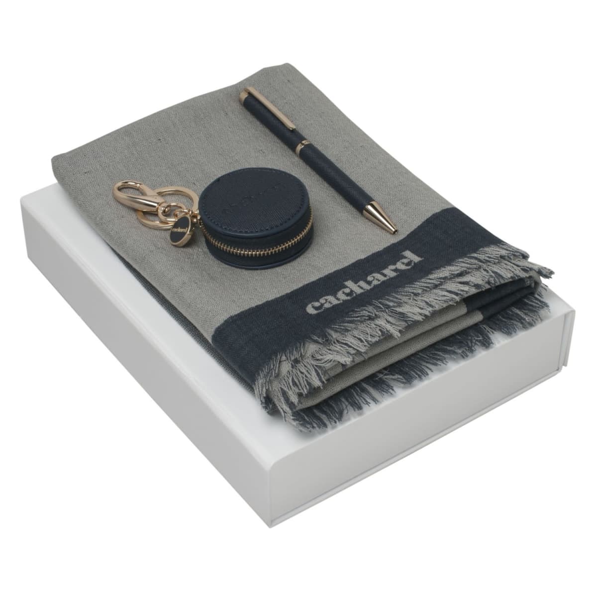 Gray scarf, pen, and round keychain case on a white box.