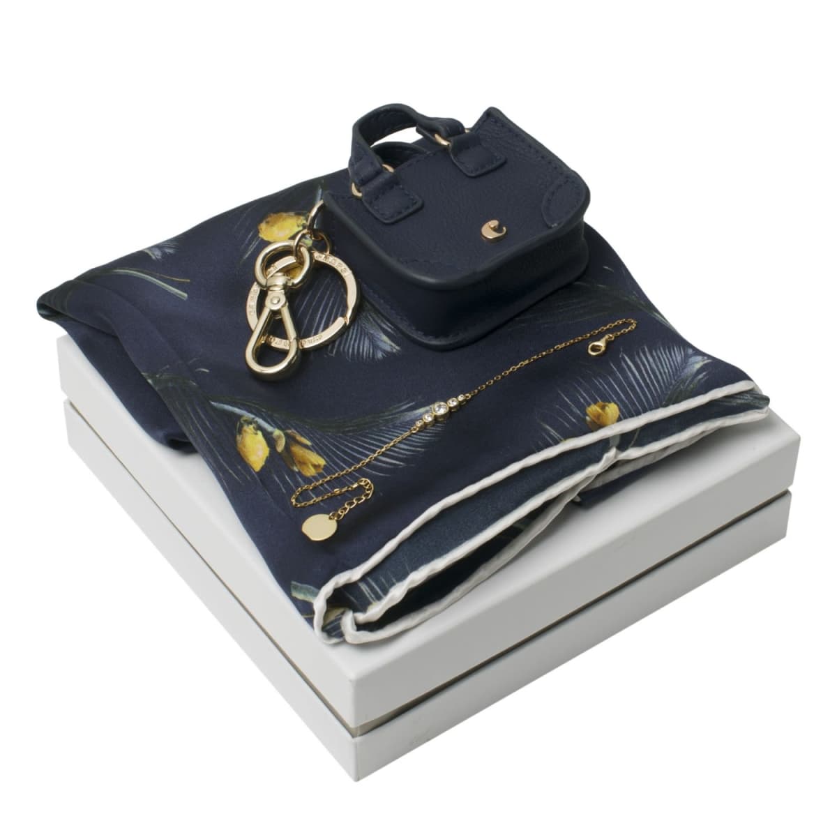 Navy scarf, mini purse, keychain, and necklace displayed on a white gift box.