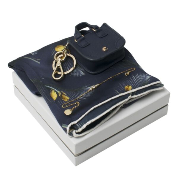 Navy scarf, mini purse, and gold jewelry arranged on a white gift box.
