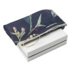 Navy floral scarf and gold bracelet on a white box.