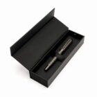 Black pen in an open black gift box on a white background.