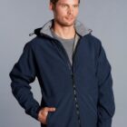 Man wearing a navy blue zip-up jacket with hands in pockets against a plain background.