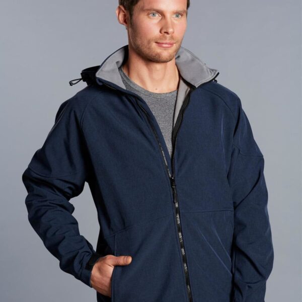 Man wearing a navy blue zip-up jacket with one hand in the pocket, standing against a gray background.